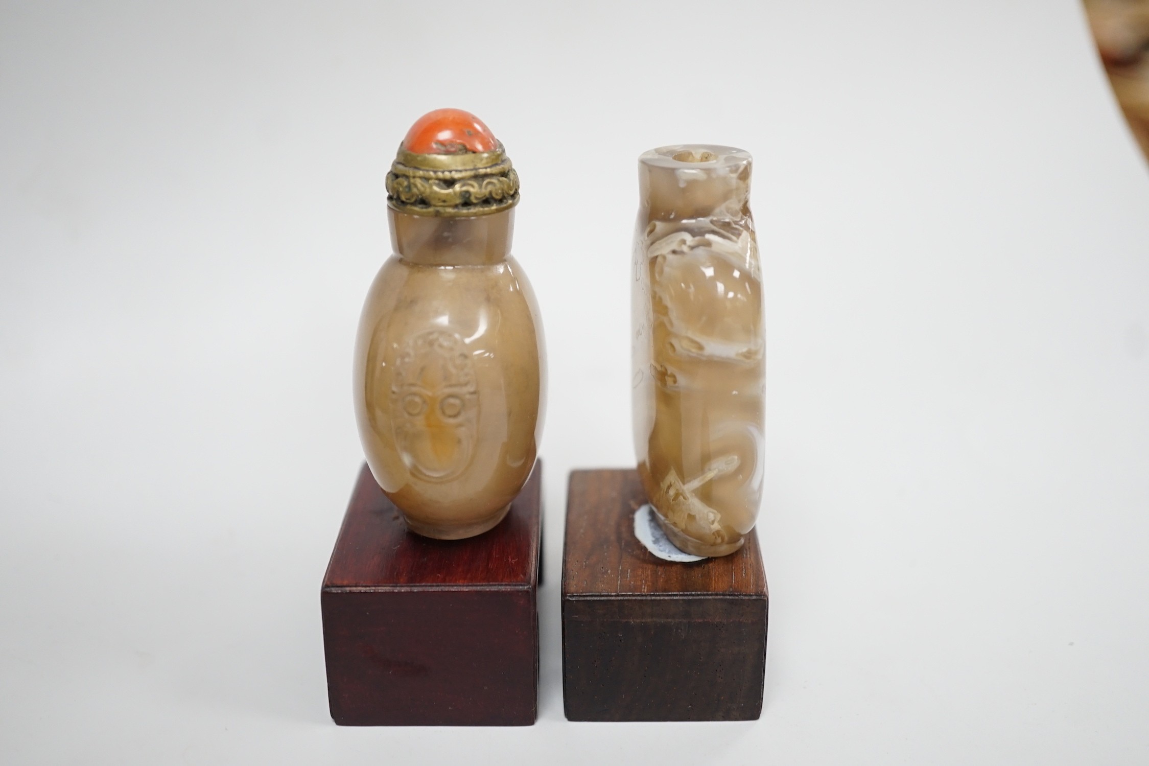A Chinese chalcedony dendritic chalcedony (macaroni agate) snuff bottle, 5.7cm and a honey coloured agate mask and ring handled snuff bottle, 4.7cm, brass and coral stopper, both 1780-1880, together with a cameo agate pi
